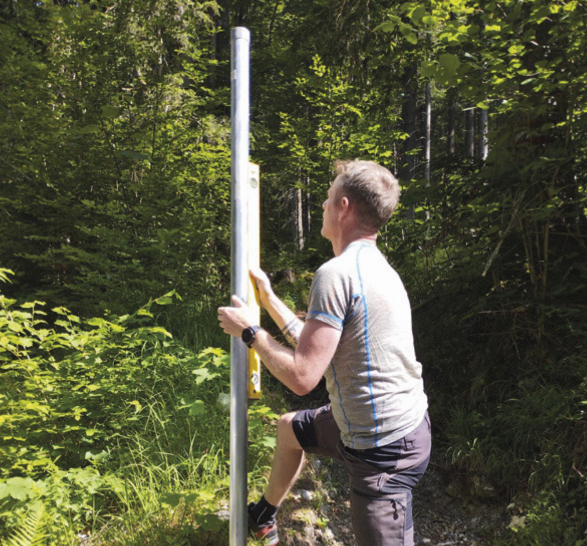 Engagement und Sorgfalt: Mit der Wasserwaage wird die Halterung für das gelbe Wanderschild gerade gerückt. Foto: NF Stainach